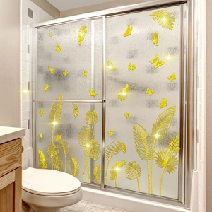 Macro shot of tropical palm leaf wall decals with gold metallic finish on a glass shower door