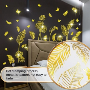 Detail of metallic hot stamping tropical leaves and feather wall stickers on grey wall