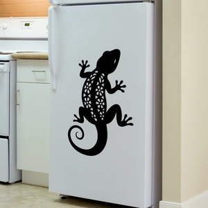 Detail of black gecko wall sticker with mandala cutout design on a modern white fridge