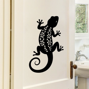 Detail of black gecko wall sticker with intricate floral cutout on a white indoor door