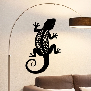 Modern black gecko wall decal with floral cutouts above a brown sofa in a cozy living room
