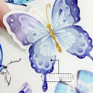 Détail macro d'un autocollant papillon phosphorescent bleu et violet avec paillettes dorées
