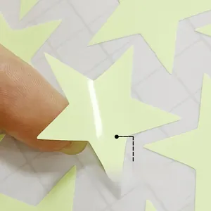 Detail view of a hand applying a glow-in-the-dark star wall sticker for room decor