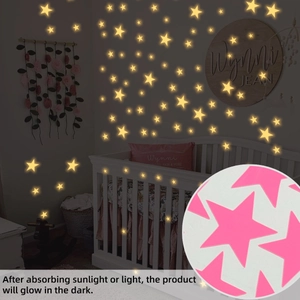 Luminous star wall stickers showing pink finish and warm yellow glow in dark room