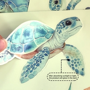 Close-up of a hand peeling a watercolor sea turtle glow-in-the-dark wall sticker