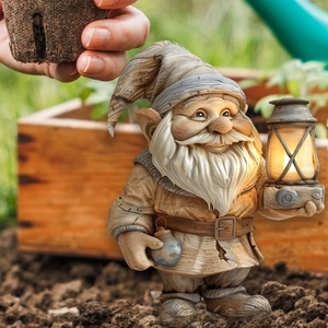 Garden gnome statue with warm light lantern and watering can for outdoor yard decor