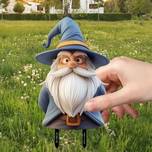 Close-up of cute gnome wizard garden stake with blue hat and white beard in a green yard