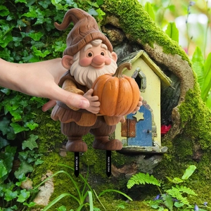 Detail of garden gnome stake holding a pumpkin with dual ground inserts for outdoor decor