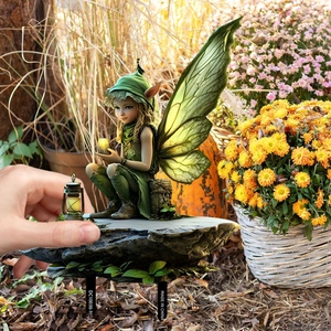 Creative green leaf fairy garden stake sitting on grey stone for outdoor decoration
