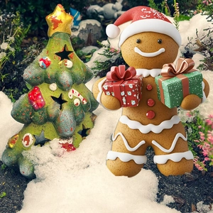 Close-up of PVC gingerbread man and Christmas tree garden stakes in a snowy yard