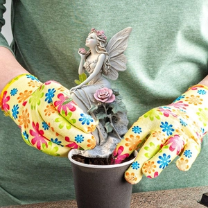 Garden fairy statue detail being placed into a pot with yellow floral gardening gloves