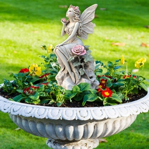 Detailed garden fairy statue with wings and pink roses in a flower pot scene