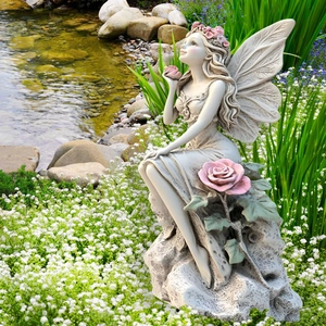 Detailed garden fairy statue with intricate wings and pink roses by a pond