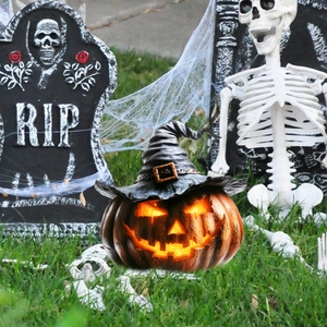 Glowing Halloween pumpkin with black wizard hat among tombstones and spider webs