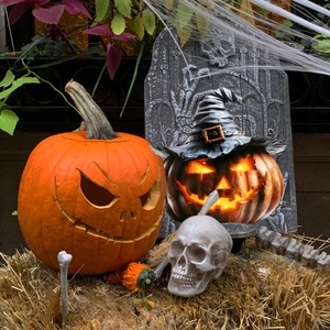 Halloween garden decor set with glowing pumpkin, witch hat, skull on hay bales