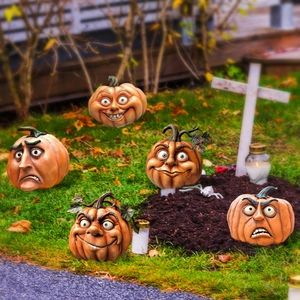 Detailed view of resin Halloween pumpkin ornaments with various expressive faces outdoors