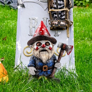 Zombie garden gnome ornament with axe on lawn next to R.I.P. tombstone decoration