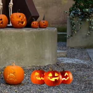 Close-up of glowing Halloween pumpkins with carved faces on stones for garden decor