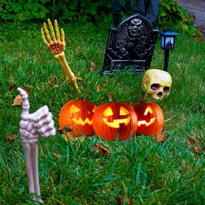 Halloween garden decor set with glowing pumpkins, skull hands, and a tombstone on lawn