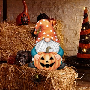 Macro-opname van een Halloween tuinkabouter die een Jack-o'-lantern pompoen vasthoudt