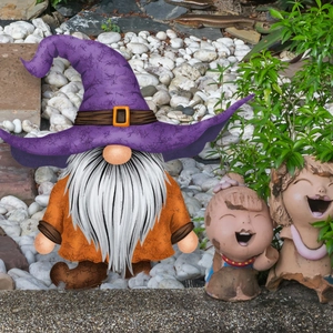 Tuindecoratie kabouter met paarse toenaarshoed en oranje jas in een buitenomgeving