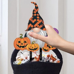 Halloween tuinsteker met kabouter en pompoenen geplaatst in een feestelijke snoepmand