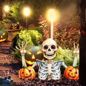 Detail van een skelet tuinpadsteker met pompoenen in een nachtelijke tuinomgeving