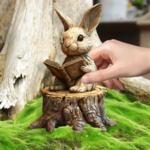 Close-up of a cartoon bunny reading a book garden stake figurine in a natural setting