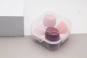 Detail of four colorful makeup sponges in a transparent box, teardrop and slanted shapes