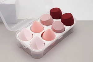 Detail of 8 makeup sponges in gradient pink and red tones inside a clear storage box