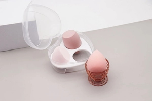 Detail of three pink makeup sponges with heart-shaped storage box and metal rose gold stand