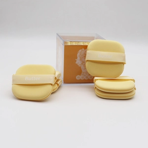 Detail of 6pcs yellow butter makeup puffs in a clear acrylic box with ribbon handles