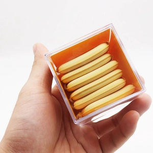 Close-up of 6 yellow butter puffs in a clear acrylic box with an orange insert