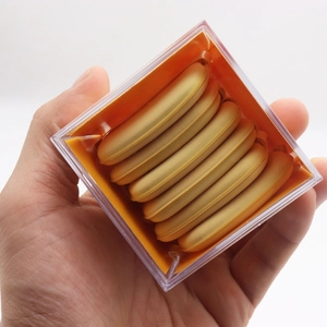Macro view of six super soft butter-colored air cushion puffs in a clear acrylic case