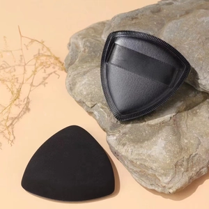 Makro-Detail einer schwarzen dreieckigen Make-up-Quaste und Kunstlederhülle auf Naturstein