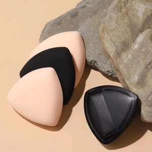 Nahaufnahme weicher dreieckiger Make-up-Schwämme in Schwarz und Beige auf Natursteinen