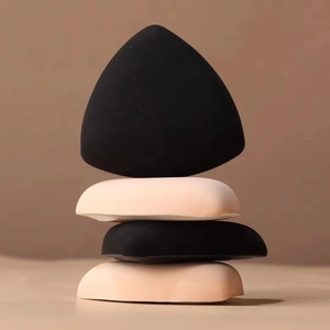 Vertikaler Stapel aus vier weichen dreieckigen Make-up-Puffs in Schwarz und Beige