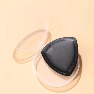 Makroaufnahme einer schwarzen dreieckigen Make-up-Quaste in einer transparenten Box