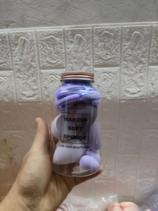 Detailed view of purple makeup sponge set with hairband in a transparent jar