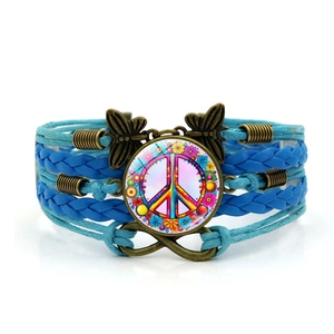 Detail of blue layered braided leather bracelet with peace sign and butterfly charms