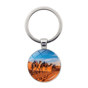 Close-up of a silver keychain with glass cabochon featuring a desert camel scene