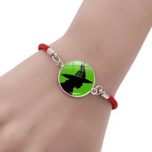 Wicked Elphaba Glinda red woven bracelet with green witch silhouette pendant detail