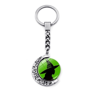 Crescent moon witch silhouette keychain with green glass pendant and intricate metal patterns