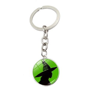 Porte-clés avec silhouette de sorcière sur fond vert et anneau métallique argenté