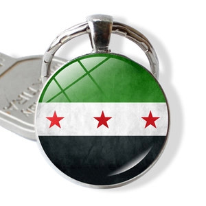Detailed close-up of a silver keychain featuring the Syrian flag under a glass dome