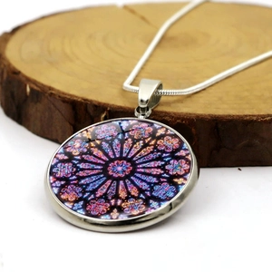 Notre Dame rose window glass pendant necklace with silver snake chain on wood base