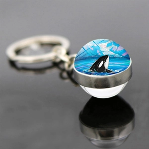 Close-up of dolphin glass ball keychain with an orca illustration and metal ring detail