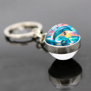 Macro view of double-sided glass ball keychain with colorful dolphin sunset ocean pattern