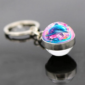 Spherical glass keychain featuring a colorful dolphin and flower illustration on dark surface