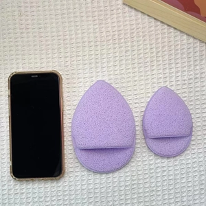 Spugne per trucco viola a goccia extra large con cinturini per dita su sfondo bianco